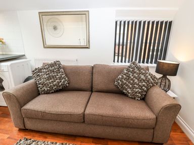 A living room with a brown sofa and a mirror at Bobby's in Whitby