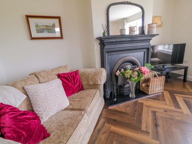 A living room with a sofa, fireplace, and television at Ard Na Mara