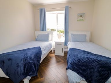 A bedroom with two single beds and a window at Ard Na Mara