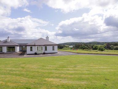 A house with a lawn and trees at Ard Na Mara