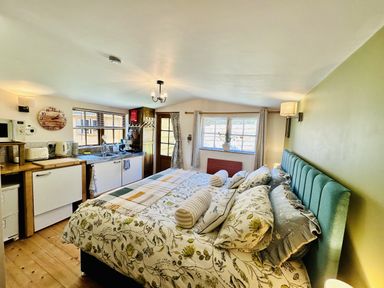 A studio apartment with a bed and kitchenette at Harvey's Lodge in Lowertown, Helston