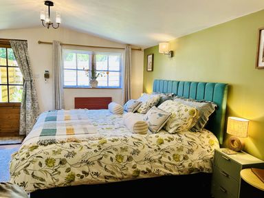 A bedroom with a bed and window at Harvey's Lodge in Lowertown, Helston