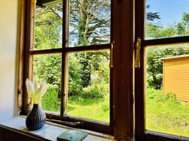 A window view with a vase and dried flowers at Harvey's Lodge in Lowertown, Helston