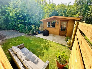 A garden with a cabin and seating area at Harvey's Lodge in Lowertown, Helston