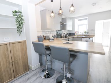 A kitchen with a countertop and bar stools at Keekle Terrace in Cleator Moor