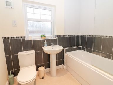 A bathroom with a toilet, sink, and bath at Lingla House in Frizington