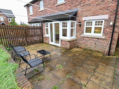 A patio area with chairs and a table at Lingla House in Frizington