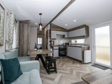 A living room with a kitchen area and dining table at Puffin in St Bees