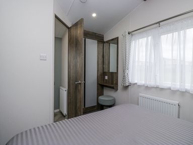 A bedroom with a bed and a mirror at Puffin in St Bees