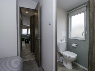 A bathroom with a toilet and a window at Puffin in St Bees