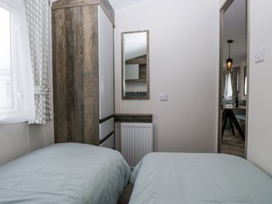 A bedroom with two beds and a wardrobe at Puffin in St Bees