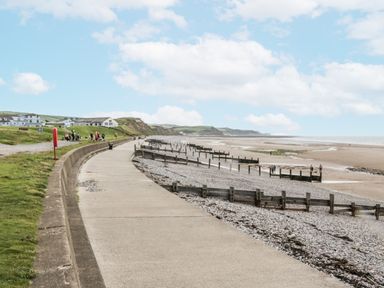 A beach with a path alongside the sea at Puffin in St Bees