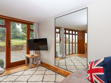 A living room with a television and large window at Church Barn in Sutcombe near Bradworthy