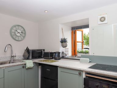 A kitchen with appliances and a window at Church Barn in Sutcombe near Bradworthy