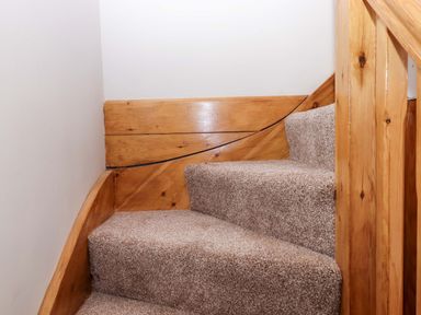 Stairs with carpet and wood railing at Church Barn in Sutcombe near Bradworthy