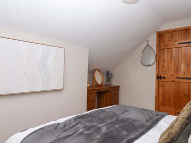 A bedroom with a bed and a dresser with a mirror at Church Barn in Sutcombe near Bradworthy