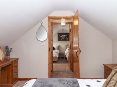 A bedroom view showing a mirror, door, and two beds at Church Barn in Sutcombe near Bradworthy
