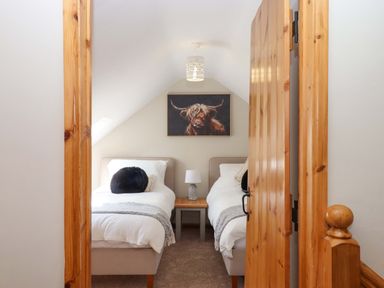 A bedroom with two beds and a painting at Church Barn Sutcombe near Bradworthy