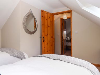 A bedroom with beds and a mirror at Church Barn Sutcombe near Bradworthy