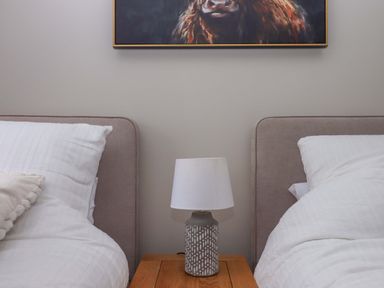 A bedroom with two beds and a lamp on a table at Church Barn in Sutcombe near Bradworthy