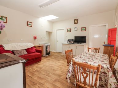 A kitchen with a table and chairs and a sofa at Kate's Cottage
