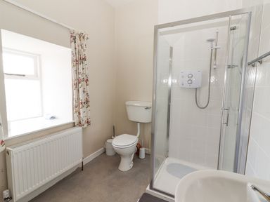 A bathroom featuring a shower, toilet, and window at Kate's Cottage