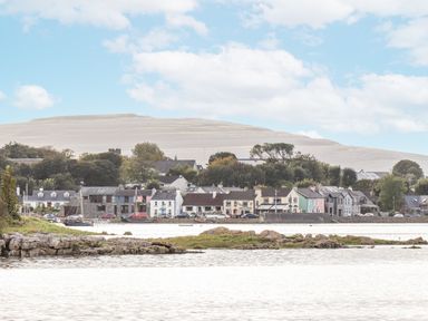 A view of houses along the water with a mountain in the background at Kate's Cottage