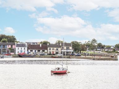 A boat on water with buildings and trees at Kate's Cottage