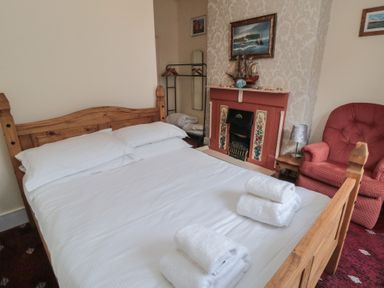 A bedroom with a bed, armchair, and a fireplace at 170 Victoria Road 