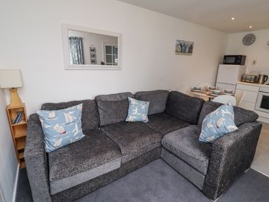 A living room with a sofa and dining area at 51 Longstone Park