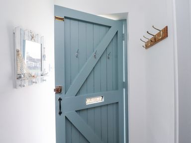 An entryway with a blue door, mirror, and hooks at 51 Longstone Park