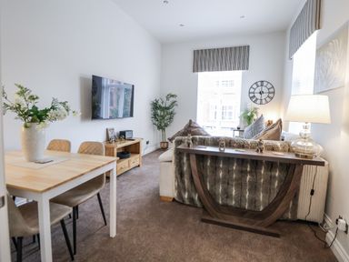 A living room with a sofa, dining table, and television at No 2 Emporium Apartments Prestatyn