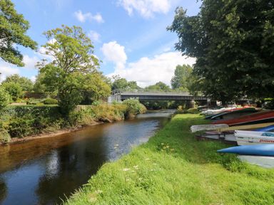 A river with a bridge and boats along the bank at St. James Cottage in St Cleer