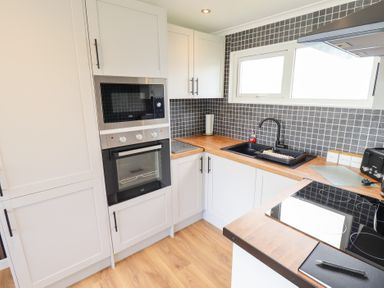 A kitchen with oven and microwave at 66 Cherry Park in Skegness