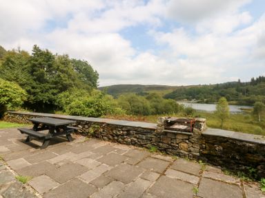 An outdoor area with a table and seating at Ty Newydd in Llanrhychwyn near Llanrwst