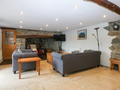A living room with a sofa and television at Ty Newydd in Llanrhychwyn near Llanrwst