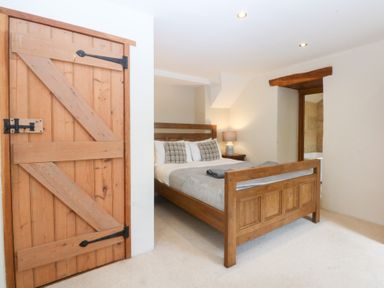 A bedroom with a wooden bed and a sliding door at Ty Newydd in Llanrhychwyn near Llanrwst