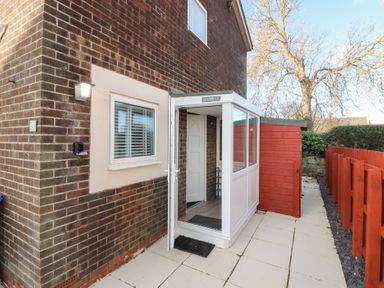 An entrance with a conservatory and paved pathway at Seaspray in Beadnell