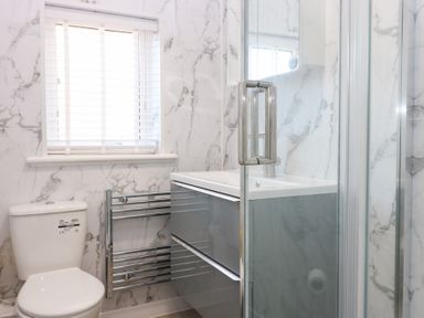 A bathroom with a sink, toilet, shower, and towel radiator at Seaspray in Beadnell