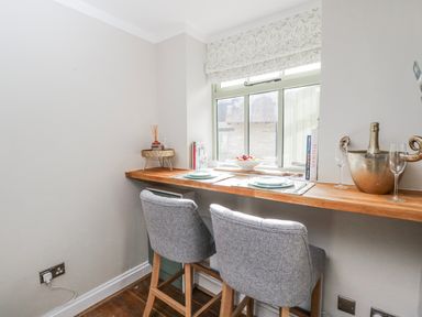 A kitchen with bar stools and a wooden table at Firefly Cottage