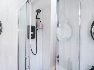 A shower with glass doors and fixtures in Firefly Cottage