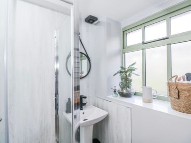 A bathroom with a shower, sink, and window at Firefly Cottage