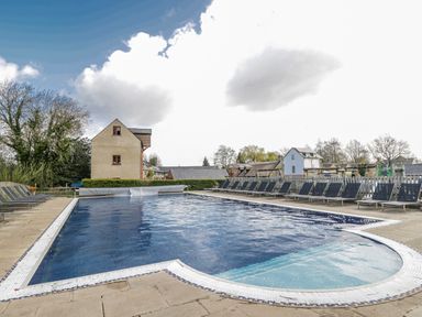 A swimming pool with loungers and buildings at Firefly Cottage