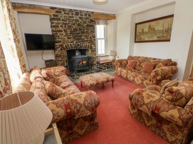 A living room with a fireplace and sofas at The Sycamores in Llawhaden near Narberth