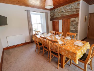 A dining room with a long table set for a meal at The Sycamores in Llawhaden near Narberth