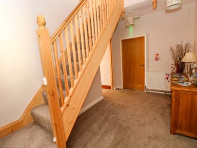 A hallway with a staircase and a table at The Sycamores in Llawhaden near Narberth