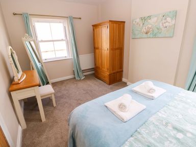 A bedroom with a bed, wardrobe, mirror, and chair at The Sycamores in Llawhaden near Narberth