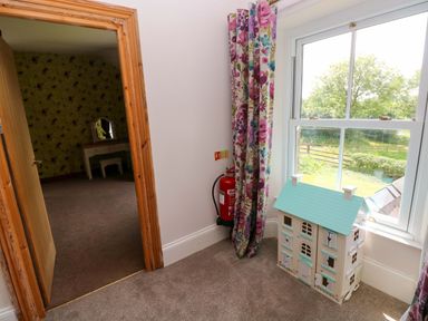 A bedroom with a dollhouse and a fire extinguisher at The Sycamores in Llawhaden near Narberth