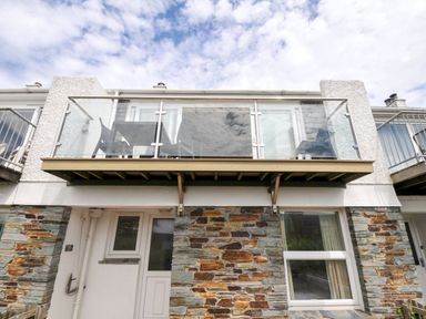 A balcony with glass railings and stone exterior at 9 Slipway Cottages Rock