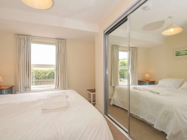 A bedroom with two beds and a window at 9 Slipway Cottages Rock